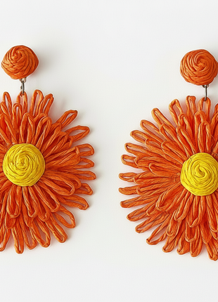 Pair of orange floral earrings with yellow centers on a white background