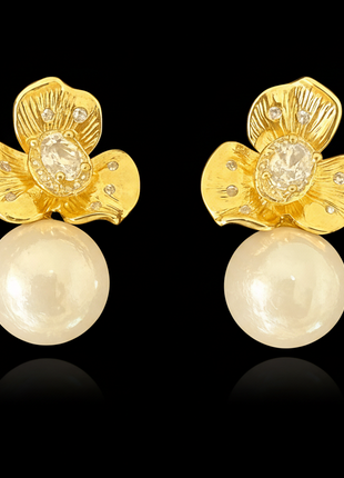 Gold floral earrings with pearl drops on a black background
