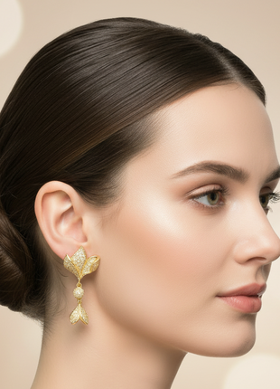 Woman wearing gold earrings with a plain background