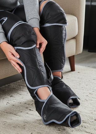 Person wearing black leg wraps sitting on a couch.