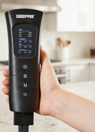 Hand holding a black electronic device with digital display and buttons, brand 'Geepas' visible, against a blurred indoor background.