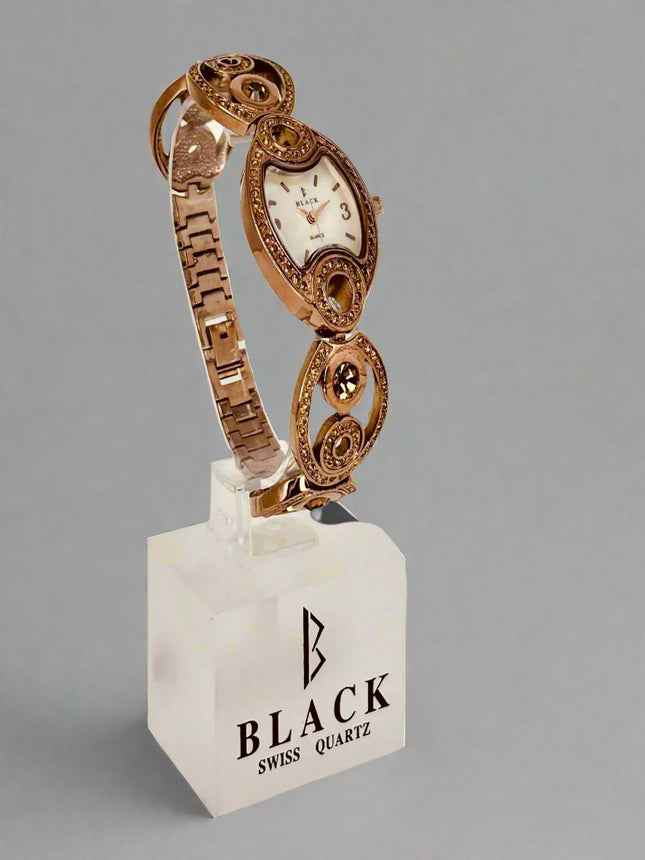 Rose gold watch on a white stand with 'Black Swiss Quartz' branding against a gray background