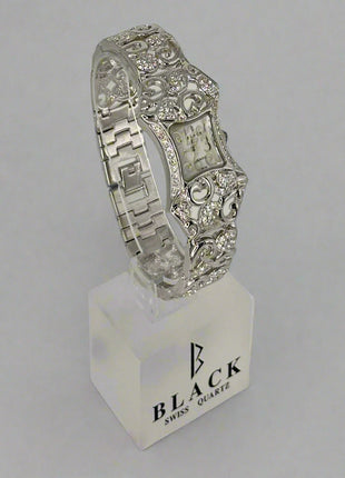 Silver bracelet on a stand with 'Black Swiss Quartz' branding against a gray background