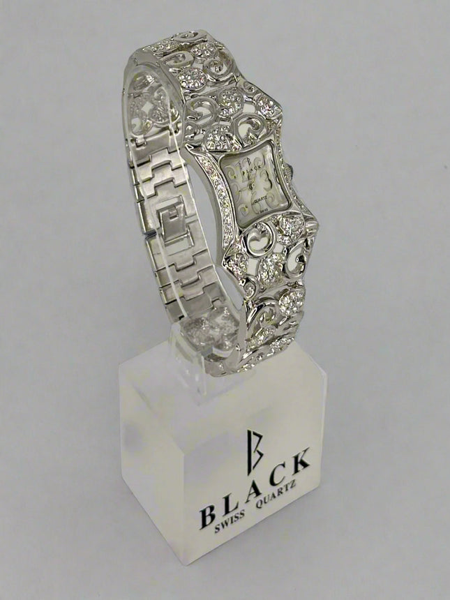 Silver bracelet on a stand with 'Black Swiss Quartz' branding against a gray background