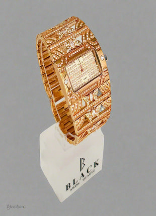 Gold wristwatch with intricate design on a gray background