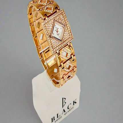 Gold bracelet with diamond accents on a white stand against a gray background