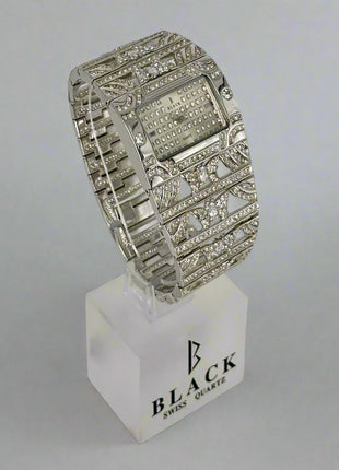 Silver wristwatch with decorative band on a white stand featuring 'Black Swiss Quartz' branding.
