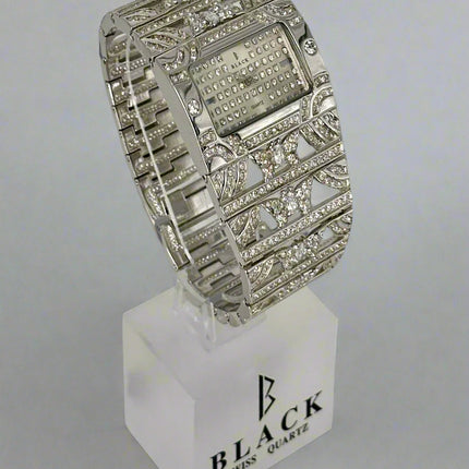 Silver wristwatch with decorative band on a white stand featuring 'Black Swiss Quartz' branding.
