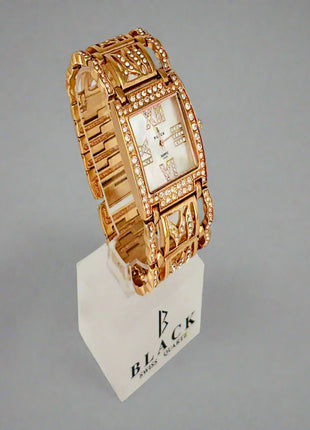 Gold wristwatch on a white stand with 'BLACK' branding against a gray background