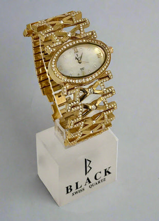Gold wristwatch with decorative design on a white stand featuring 'BLACK SWISS QUARTZ' branding.