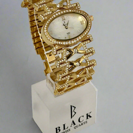 Gold wristwatch with decorative design on a white stand featuring 'BLACK SWISS QUARTZ' branding.