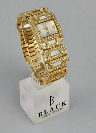 Gold wristwatch on a white stand with 'BLACK' branding