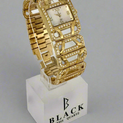 Gold wristwatch on a white stand with 'BLACK' branding