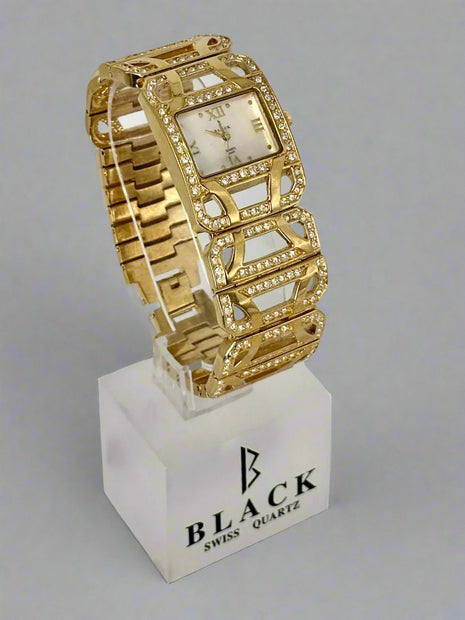 Gold wristwatch on a white stand with 'BLACK' branding