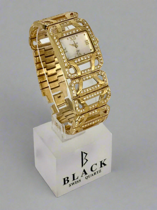 Gold wristwatch on a white stand with 'BLACK' branding