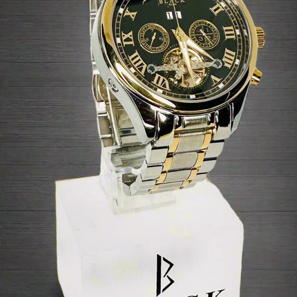 Two-tone watch with black face and gold accents on a white stand with 'BLACK' branding.