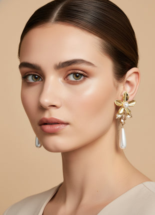 Woman wearing gold floral earrings with a beige background