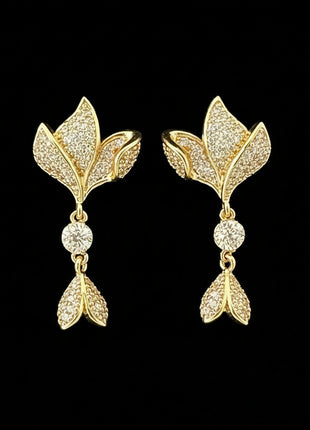 Gold leaf-shaped earrings with diamond accents on a black background