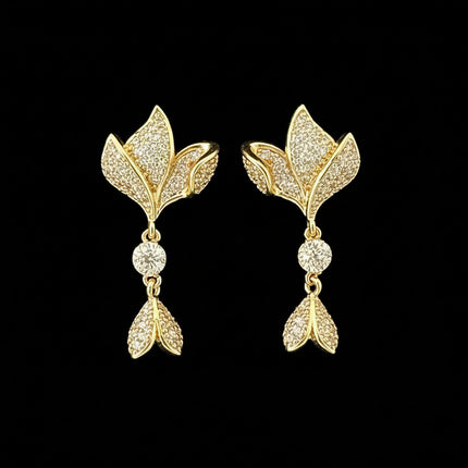 Gold leaf-shaped earrings with diamond accents on a black background