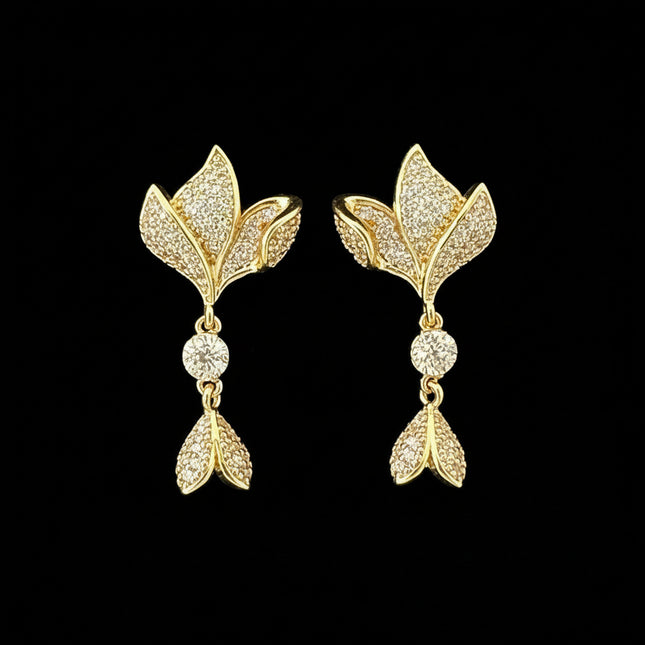Gold leaf-shaped earrings with diamond accents on a black background