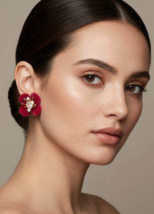 Woman wearing a red floral earring against a neutral background