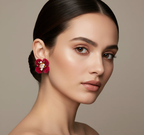 Woman wearing a red floral earring against a neutral background