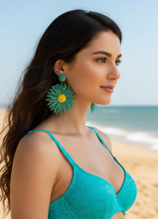 Woman wearing a floral dress and green earrings in an outdoor setting with people and flowers.