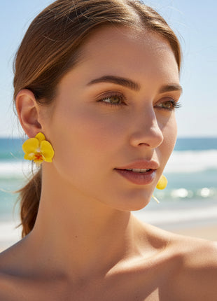 Woman wearing yellow flower earrings on a beach