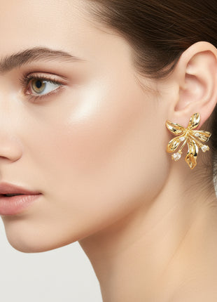 Close-up of a woman wearing a gold earring on a light background
