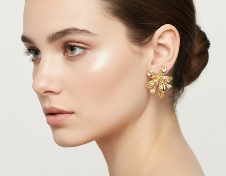 Close-up of a woman wearing a gold earring on a light background