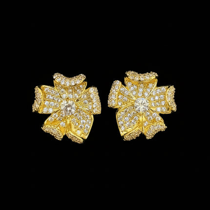Gold floral earrings with clear stones on a gray background