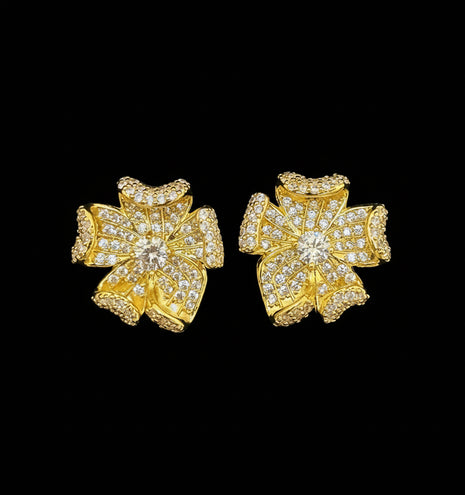 Gold floral earrings with clear stones on a gray background