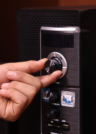 Hand adjusting a knob on a stereo system with a dark background