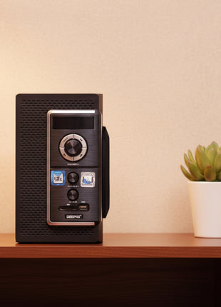 Black electronic device with a silver knob on a wooden surface next to a plant