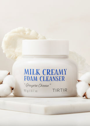 Jar of Milk Creamy Foam Cleanser with a scoop of foam on a white background