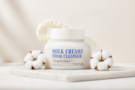 Jar of Milk Creamy Foam Cleanser with a scoop of foam on a white background